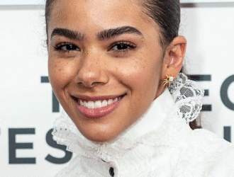 Close up professional headshot of a young woman with a warm smile wearing a white lace blouse and minimal jewelry