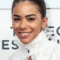 Close up professional headshot of a young woman with a warm smile wearing a white lace blouse and minimal jewelry
